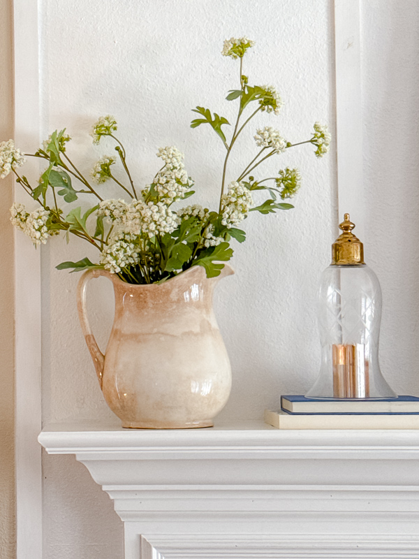 Vintage stoneware pitcher with white flowers and a glass cloche on a white fireplace mantel for Ralph Lauren Americana home decor