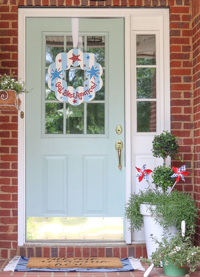 Simple patriotic porch decor with a Coton Colors wreath, pin wheels, and white flowers