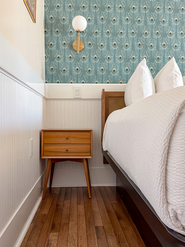Mid-century modern nightstand against traditional wainscoting and wallpaper