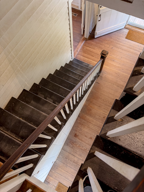 How to make your new house look old. Stairs in Belleview stained dark with white railing and white shiplap walls.