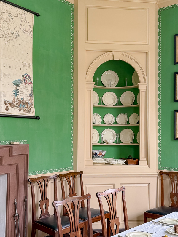 Green dining room with white pedimented door surround at Colonial Williamsburg. Brighter colors were used in the 1700s in upper scale homes.