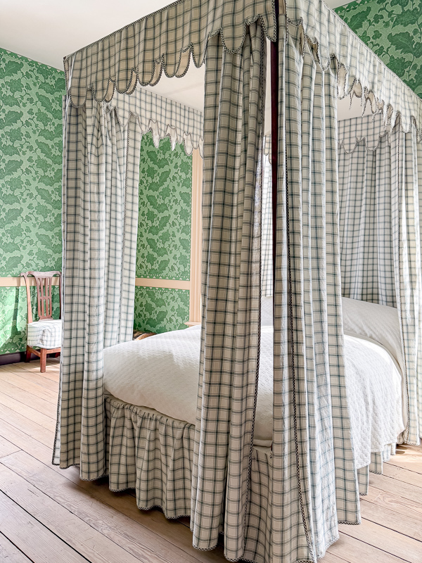 Blue check canopy bed against leaf print wallpaper found at Williamsburg VA.