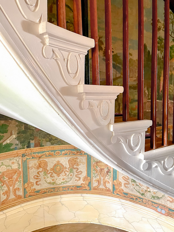 Ornate stairs in The Hermitage with mural on wall and painted white side of stairs detail. Great idea for a new house build.