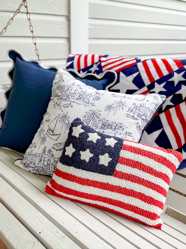 Red, white and blue pillows on a porch with an American flag pillow and throw blanket