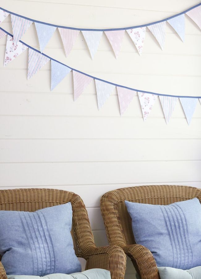 Handmade paper pennant banner in softer red, white, and blue hanging on a back porch wall.