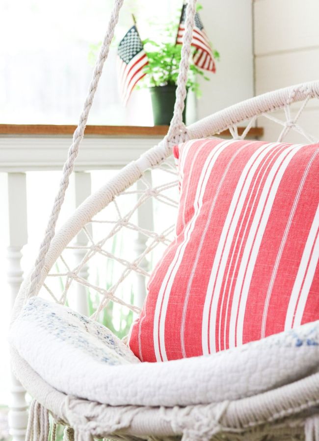 Red and white striped pillow and American flag pillow on a hammock swing porch chair