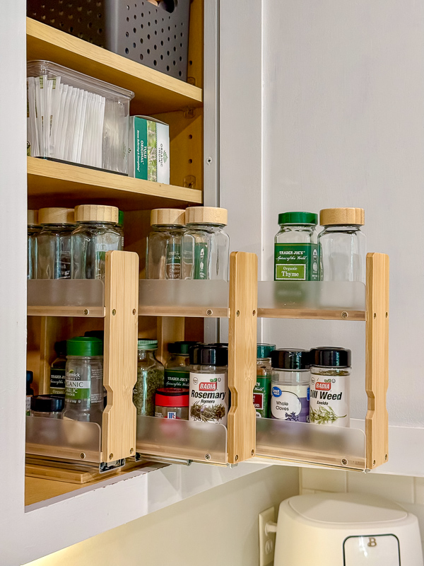 Before photo of a cluttered spice cabinet with mismatched jars crammed onto pull-out drawers, showing why a spice organization upgrade was needed