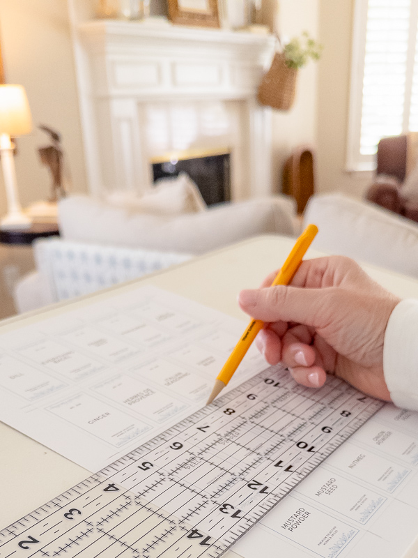 Using a mechanical pencil and ruler to trace guidelines on printed spice label sheets for clean, easy cutting