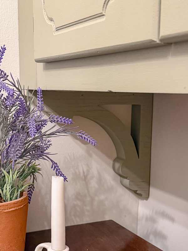 Large decorative brackets painted green under a cabinet