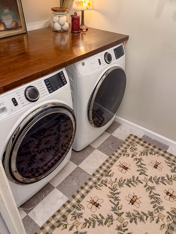 Whimsical garden laundry room with butcher block countertop in dark stain and ge washer and dryer.