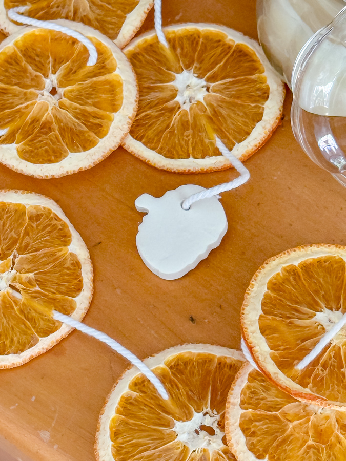 Tiny white air dry clay pumpkin tied to the end of a dried orange strand
