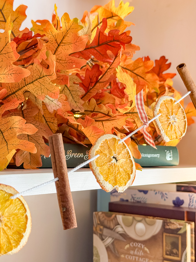 Close-up of a dried orange slice, cinnamon stick, and gingham bow on a fall garland
