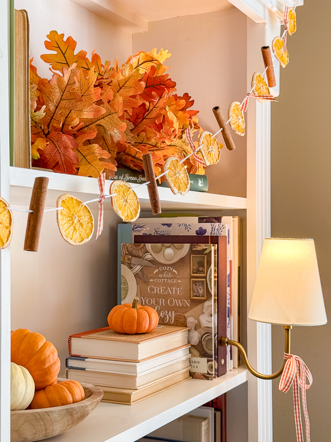 Dried orange fall garland on a bookcase with a lamp tied with gingham ribbon