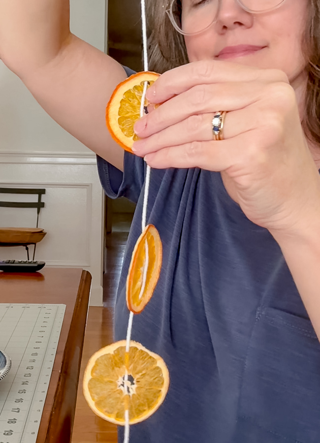 Holding up a finished strand of dried orange slices for a window suncatcher