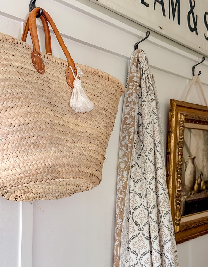 Handmade paper leaf garland with mini pinecones and fairy lights hanging beside the gilt-framed pitcher and pears print