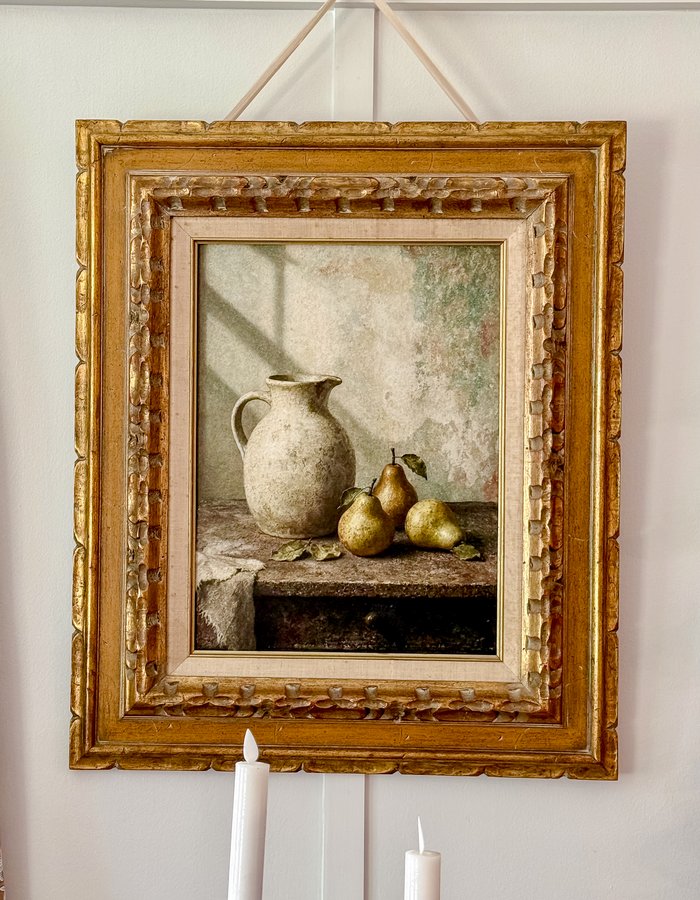 Wider view of the small gilt pear painting with the dried leaf basket and green pothos plant below it