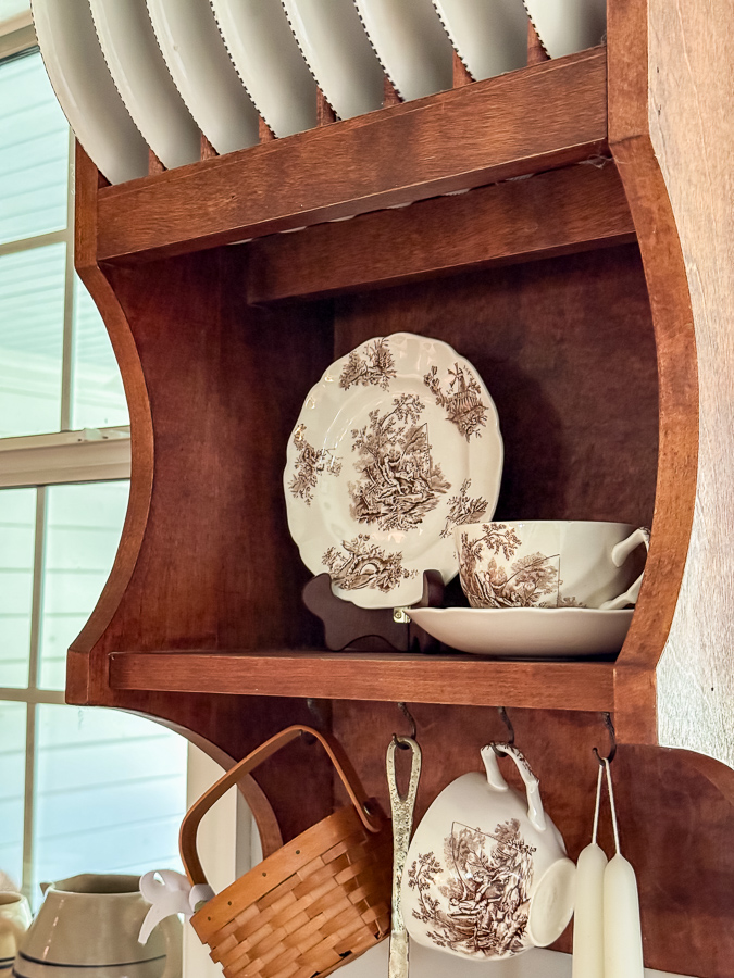 Brown and white china dishes on a homemade wood shelf in a kitchen for a fall french country decorating idea.