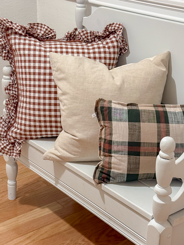 Autumn pillows in green, tans and rust reds on a white bench