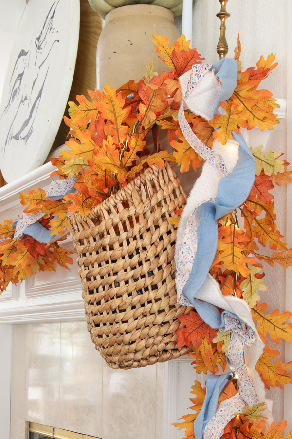 Lighted fall leaf garland with torn chambray and floral fabric strips spilling from a woven hanging basket