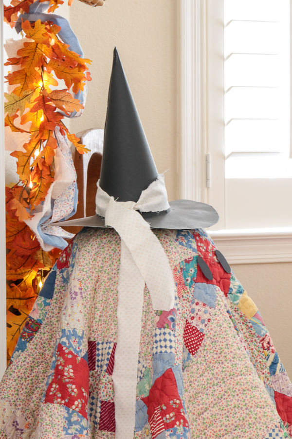 Close-up of a quilt ghost's black paper witch hat tied with a frayed white fabric ribbon
