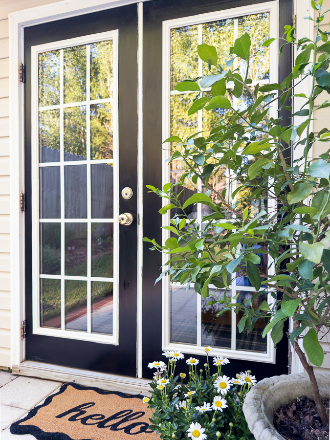 Black French patio doors painted Tricorn Black with white trim and a potted orange tree