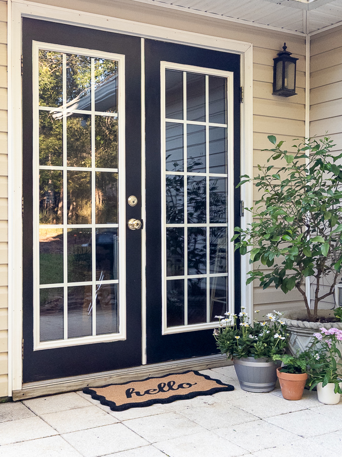Finished black French patio doors painted Tricorn Black with white trim on a cozy patio
