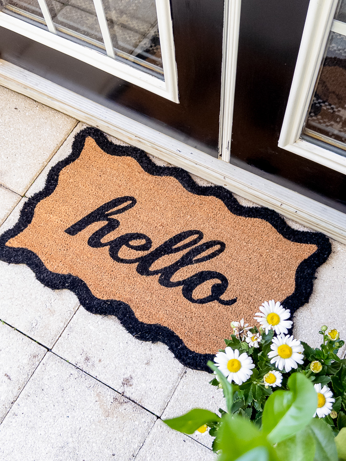 Scalloped hello doormat in front of black French patio doors with white trim