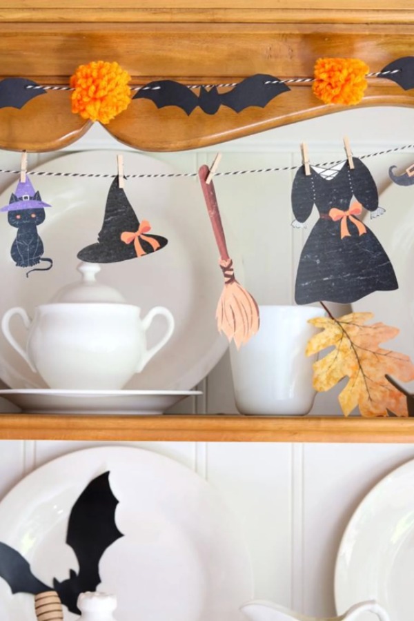 DIY mini witch hat garland with a black cat, broom, and witch dress cutouts clipped to twine.