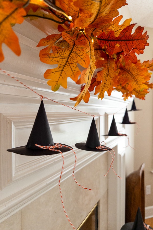 Mini paper witch hat garland strung on twine along a mantel.