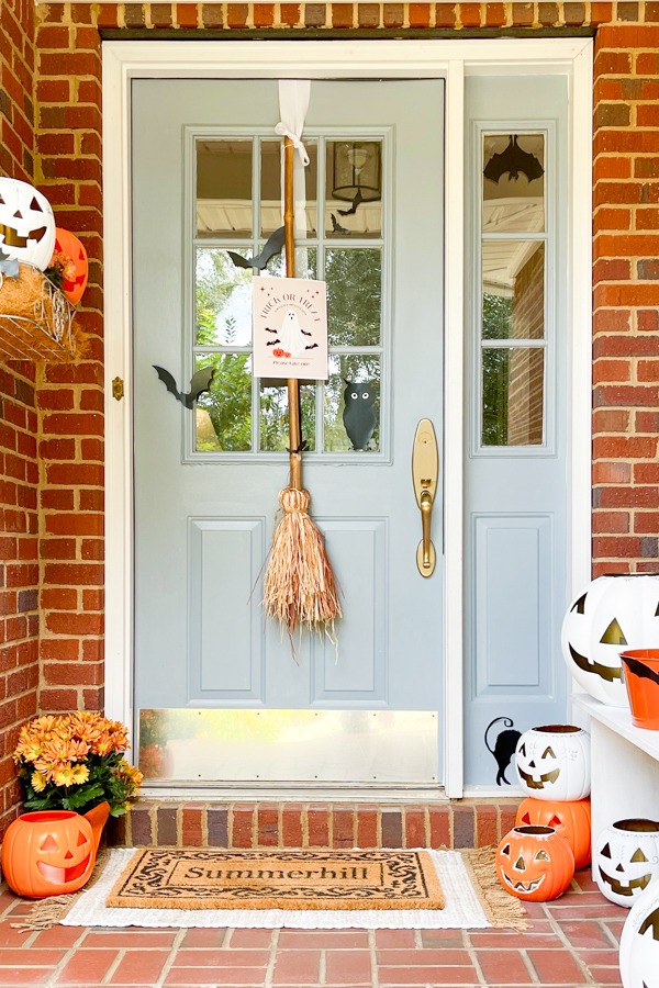 Trick-or-Treat printable sign hanging from a witch’s broom tied to the front door.